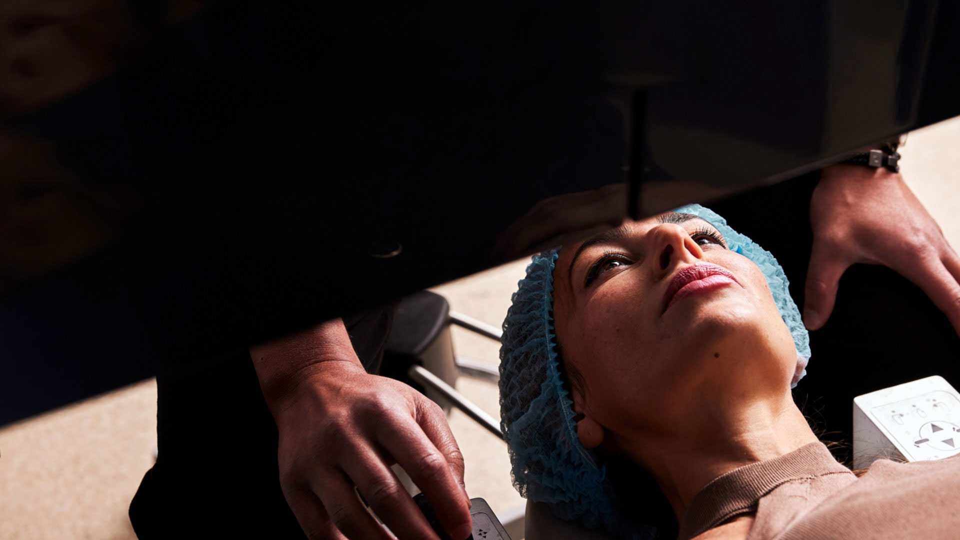 Woman wearing blue hat receiving eye examination